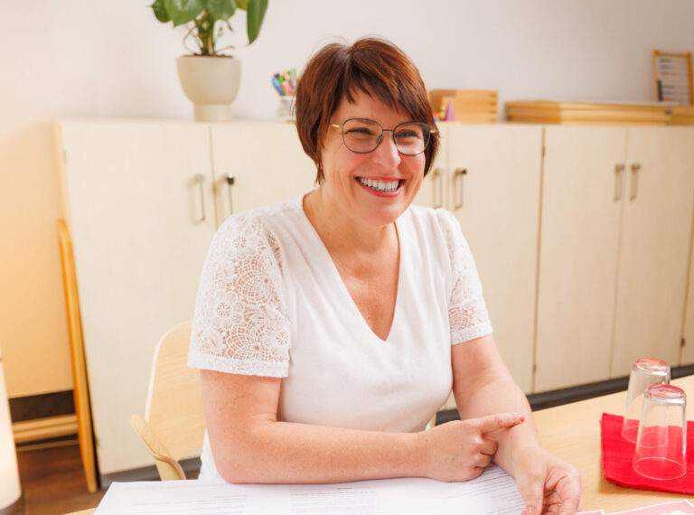 Lächelnde Frau an einem Tisch in der Praxis