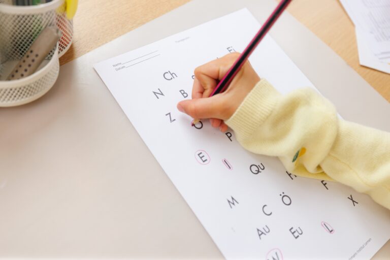 Kind schreibt Buchstaben auf ein Arbeitsblatt