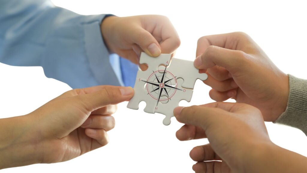 Hände halten ein Puzzleteil mit Kompass-Symbol